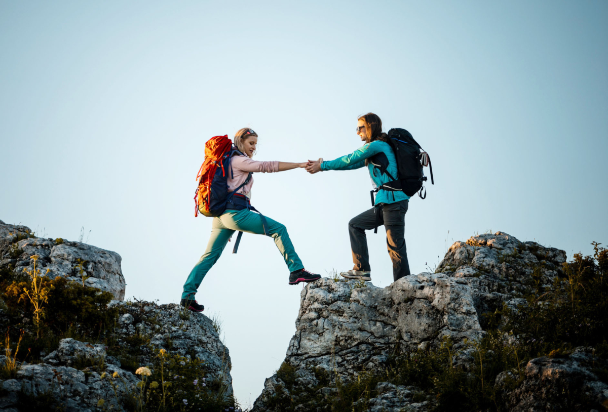 a man helps a woman climb a mountain