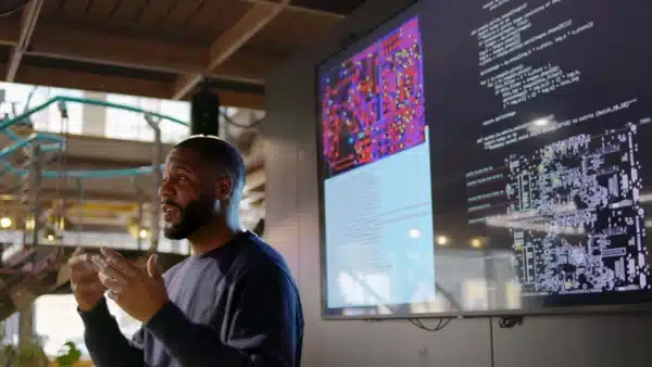 a man is giving a presentation in front of a large screen