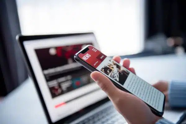 a person is holding a cell phone in front of a laptop computer