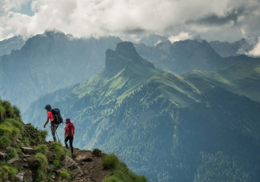 two people with backpacks are hiking up a mountain